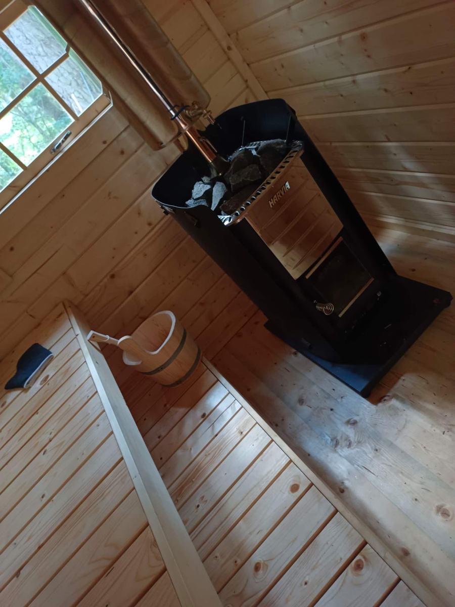 Dřevěná sauna s lavicemi, kamny a vědrem